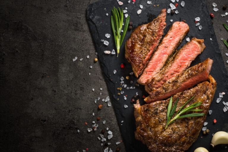 Grilled beef steak on black table.